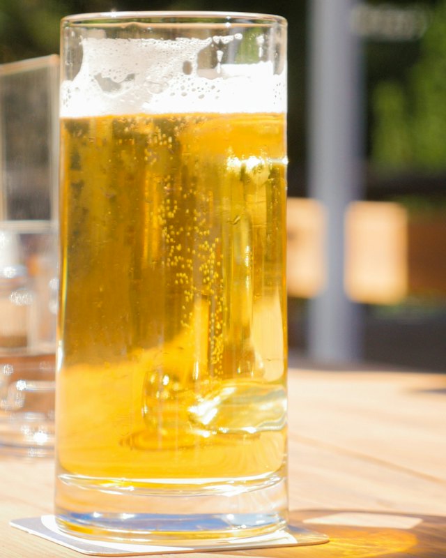 Eine Maß Helles auf einem Biergartentisch in der Sonne