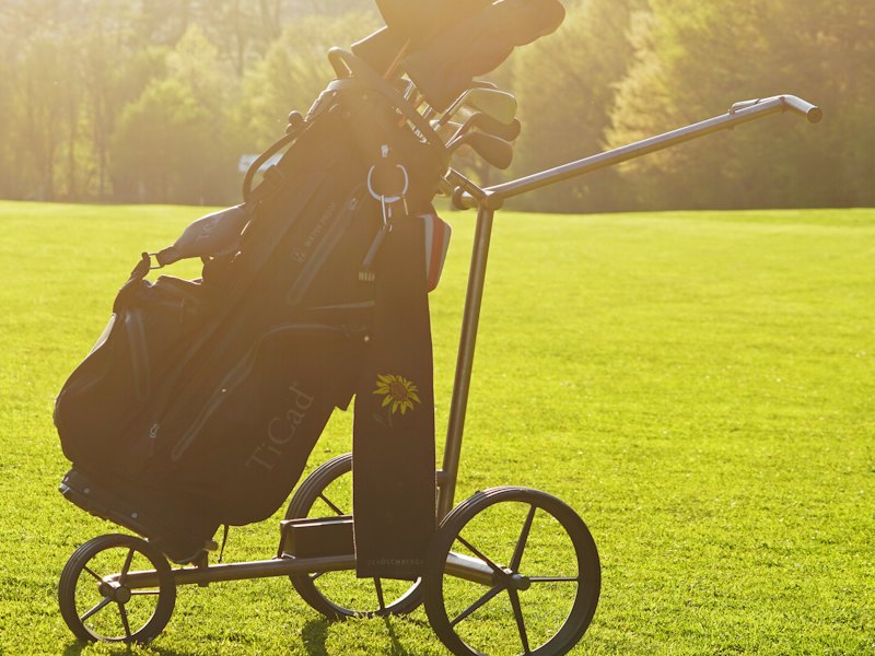 Golfbag auf einem Trolley im Abendlicht auf dem Fairway